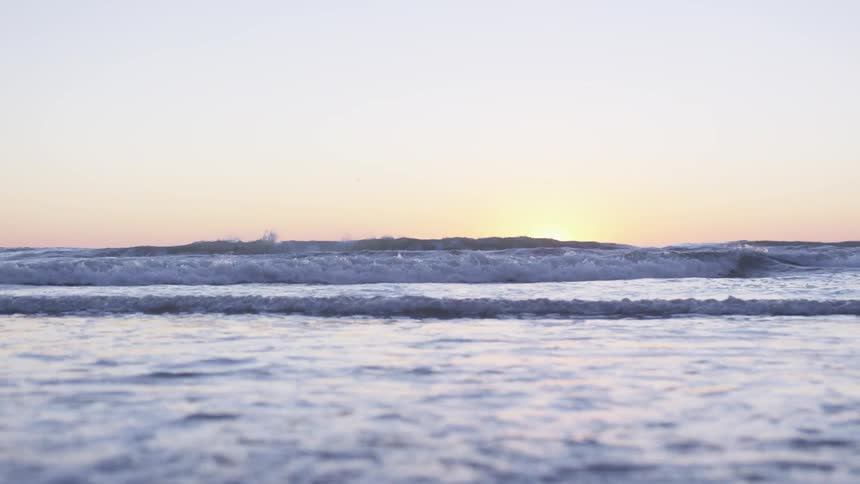 Waves rolling in towards the shore at sunset