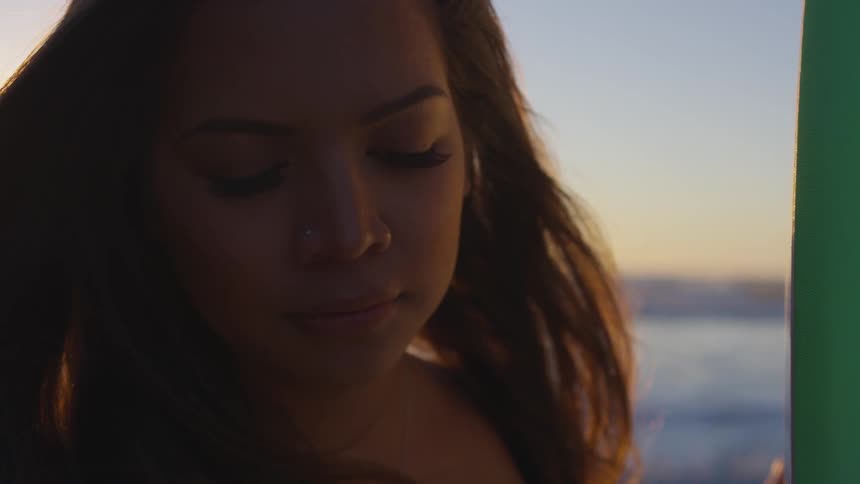 Woman closes eyes while the sun goes down behind
