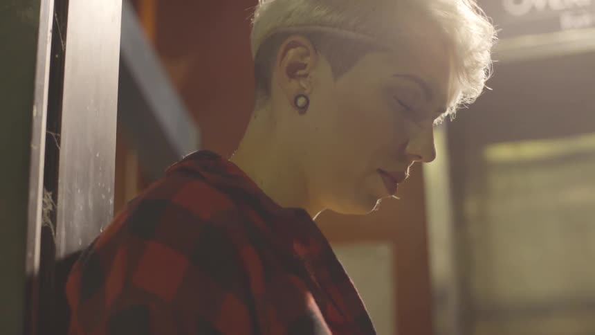 A woman leans against a wall while looking down