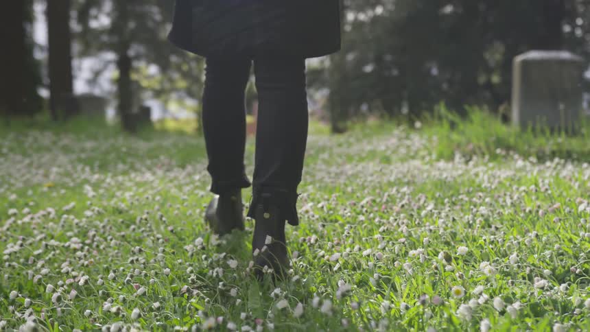 Person walks through grass in a cemetery
