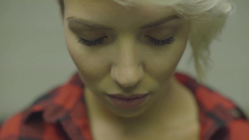 A young woman rides an elevator while looking down