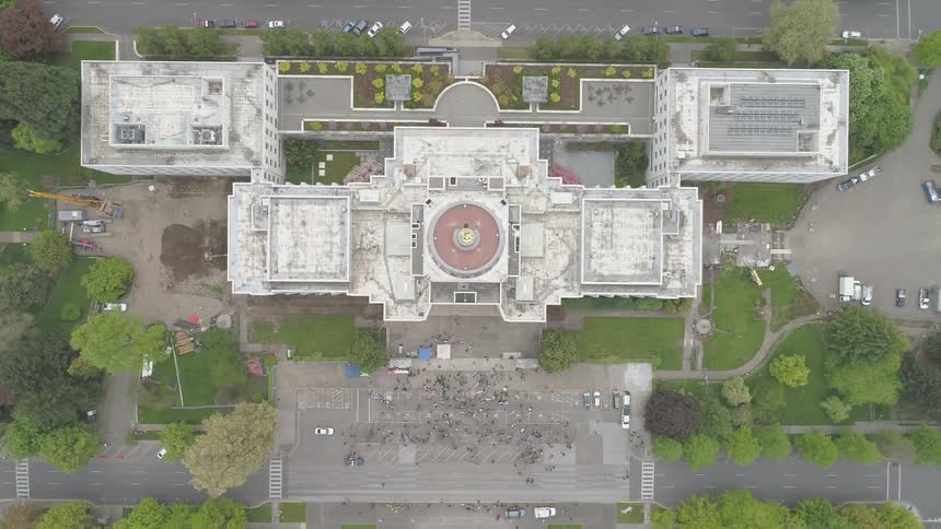 Camera looks down on a large building and crowd
