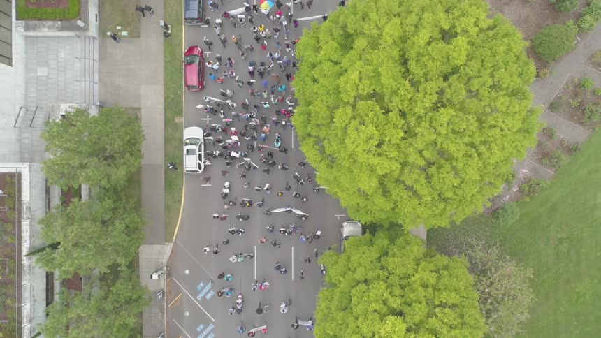 A parade of people walk down a city street carrying banners