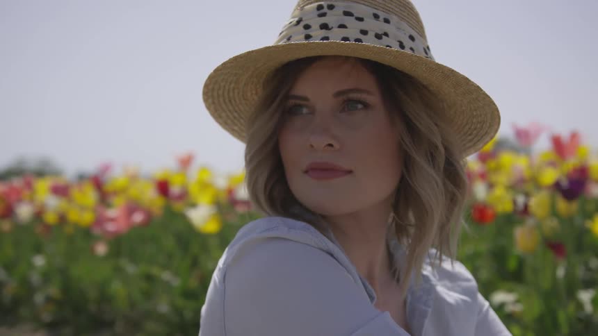 Woman wearing a hat sits on a tulip field
