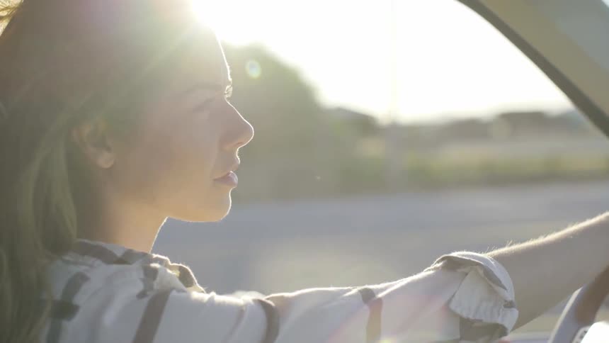 A woman driving a vehicle on a sunny day