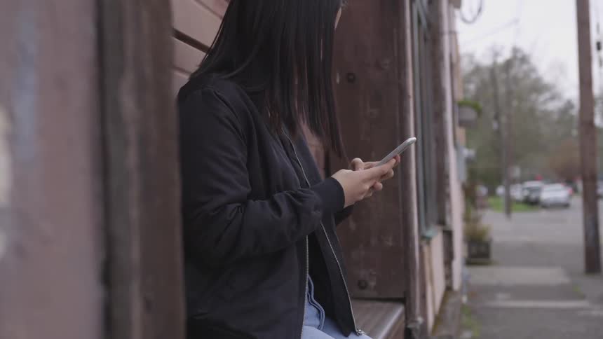 A woman is outside looking at her phone