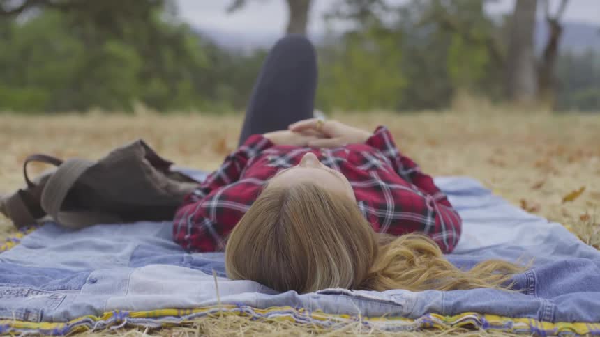 Girl laying on blanket in field looking up at sky