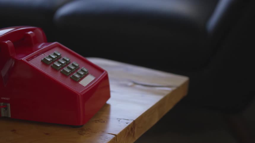 Red phone sits on table next to couch