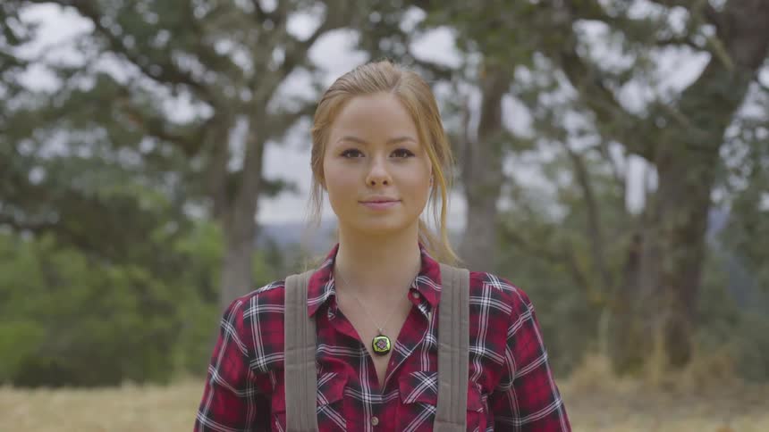 Young blonde haired girl stands in front smiling