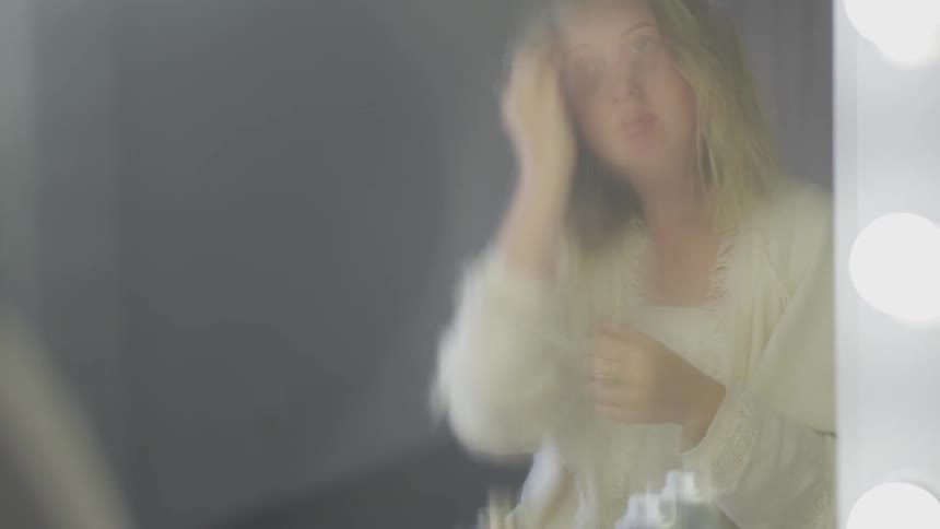 A young woman teases her hair in front of a mirror