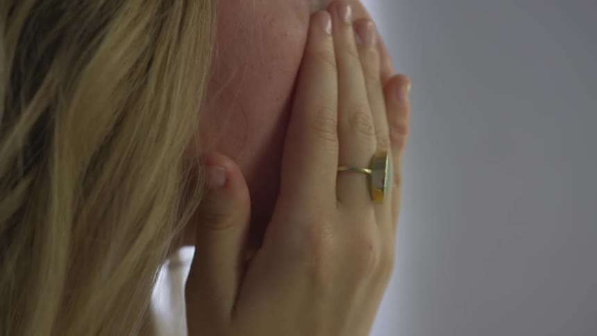 Woman rubs lotion into her face