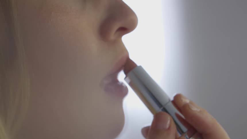 A woman puts on lipstick