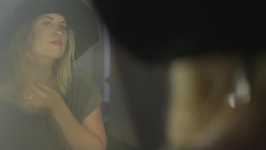 Woman wearing hat admires herself in the mirror