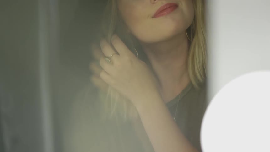 A young woman stands and plays with her hair