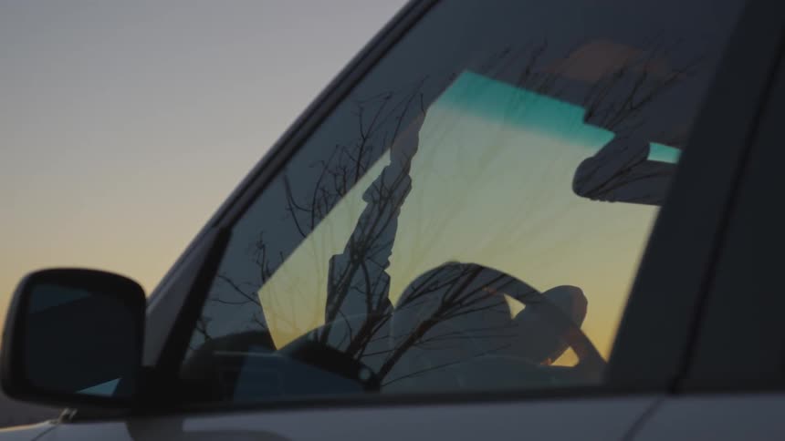 A person is laying on top of a car