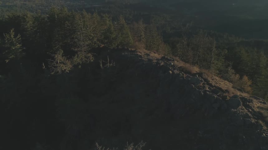 Man climbs over the rocks on top of a large hill