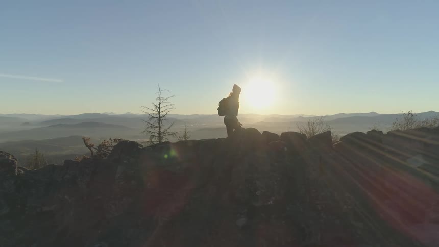 A woman hikes along a mountain ridge at sunrise