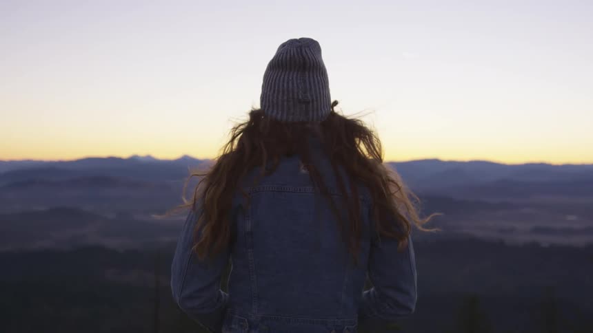 A young woman stands and looks at the horizon