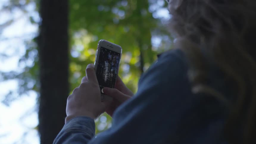 A woman is holding a phone and taking pictures with it