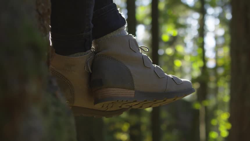 Feet are crossed while someone sits on a tree