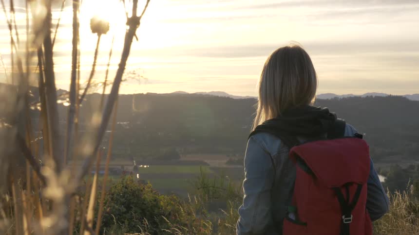 She is standing there looking down into the valley with her red backpack on