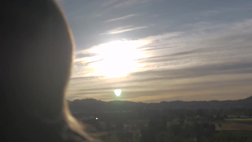 Woman watches the sunrise over the mountains and valley