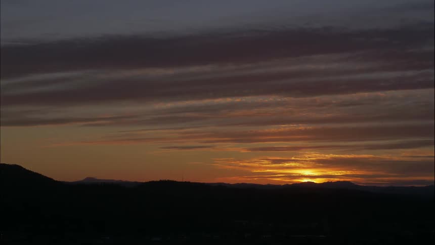 Clouds float over mountains at sunset