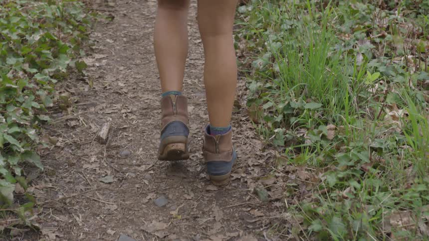 A woman walks down a dirt path