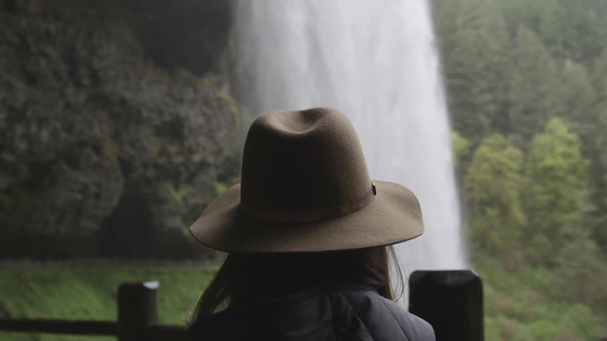 Woman watches a waterfall cascade down