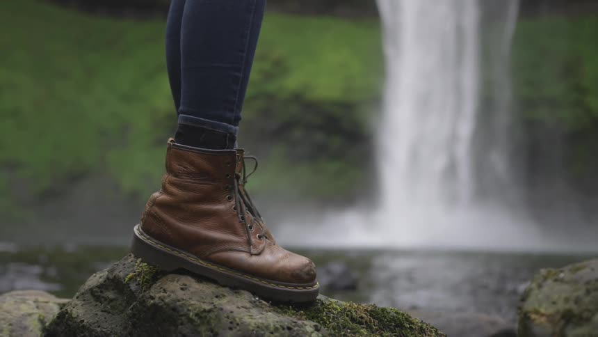 Woman stands on a rock near a waterfall