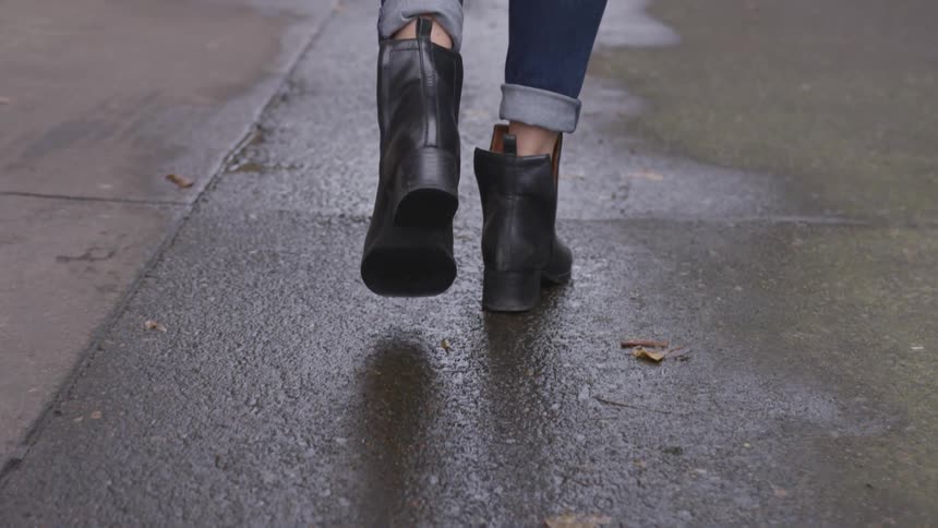 A woman walks along a wet street
