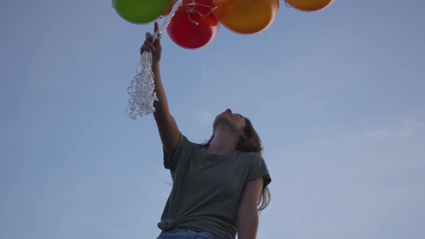 Woman holds strings to a bunch of balloons