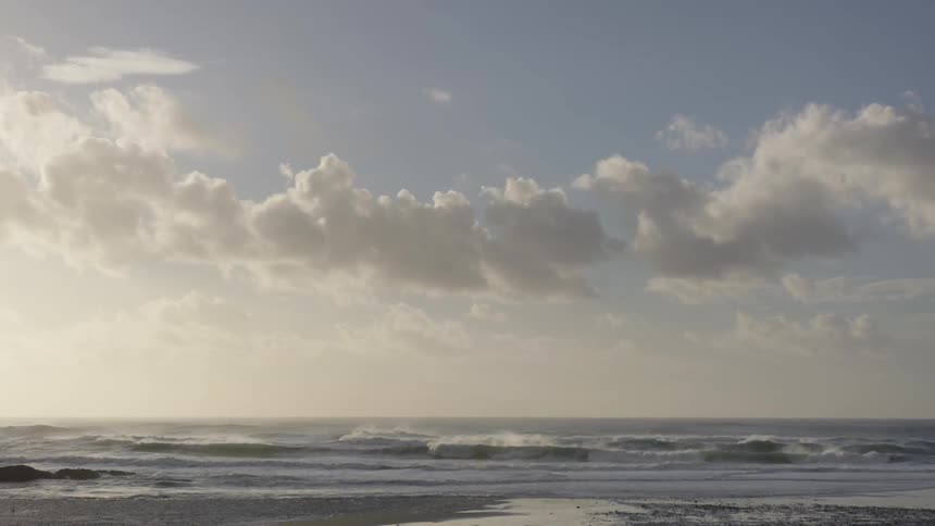 Ocean waves at sunrise under a cloudy sky