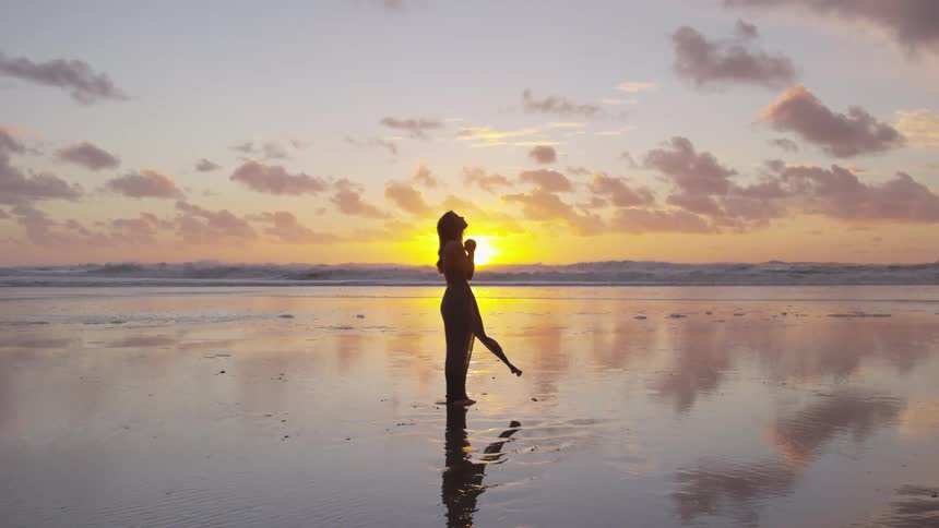 Woman praying and looking up to the sky while standing at the beach