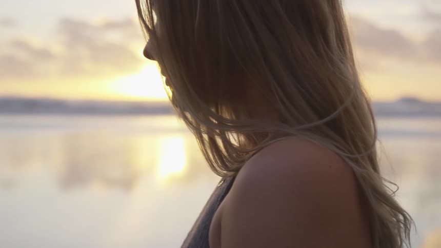 A woman looking over a lake at sunset