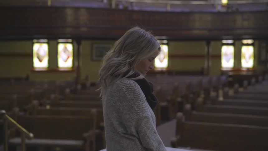Woman bows her head and prays in a church