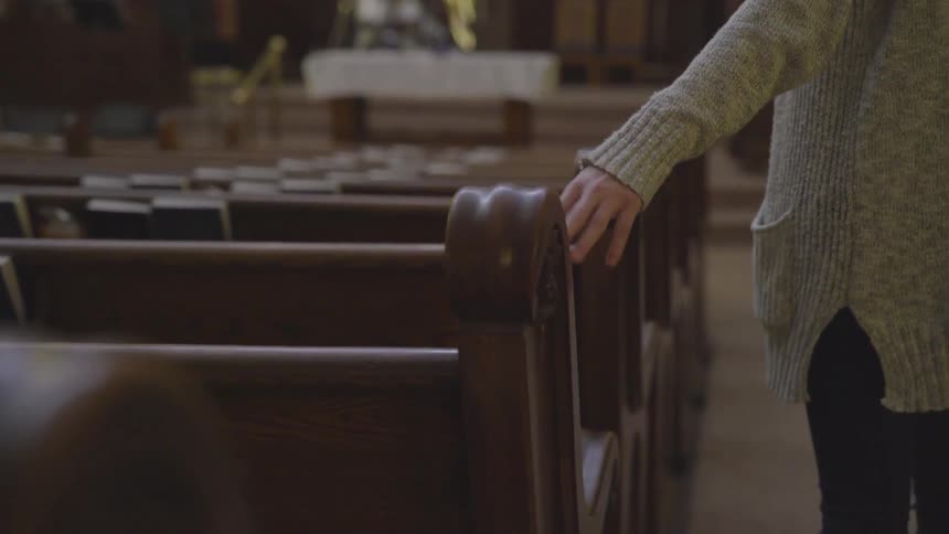 A person glides their hand along pews