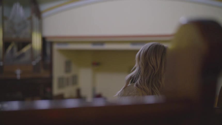 Woman sits in a high up church pew