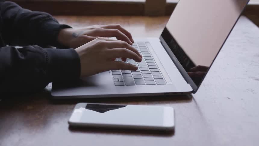 Person types on a laptop on a table