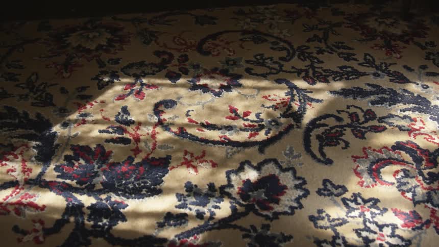 The shadow of a hand moving along a carpet