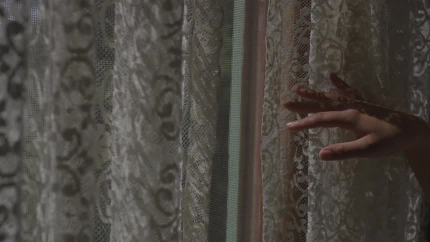 A person opens up a closed curtain