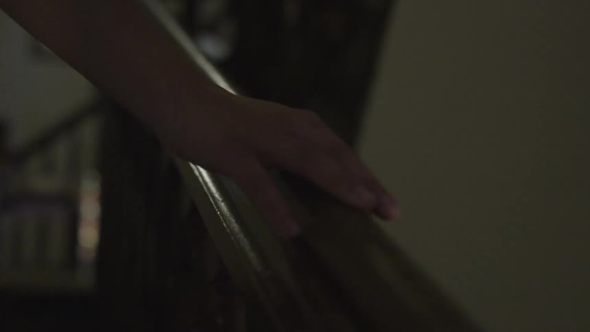Person walks up stairs with hand on banister