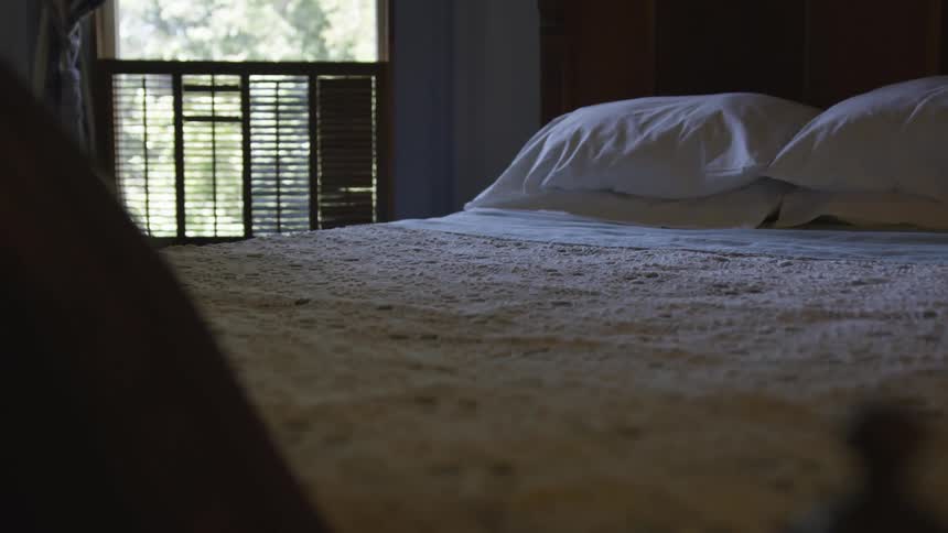 Made bed next to shuttered window