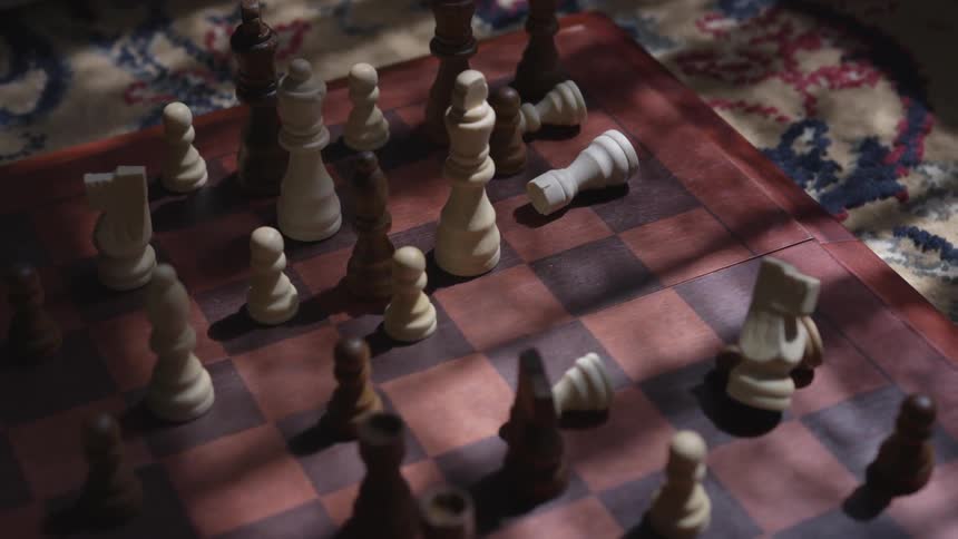Something shakes a chessboard and some figures fall down