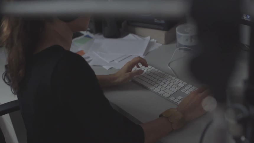 A white female sitting at a desk typing on a computer