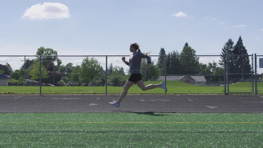A woman in athletic shorts run on an outdoor track