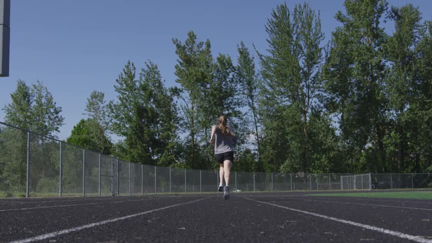 Woman runs on running track in the daytime