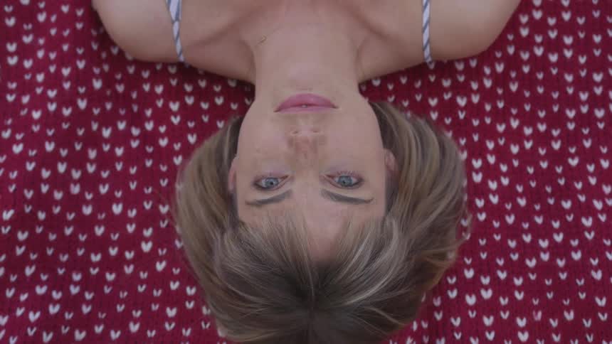 White woman opening her eyes while lying in a towel outdoors