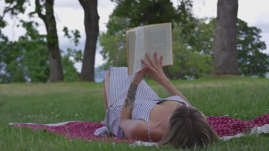Woman lies in the grass reading a book