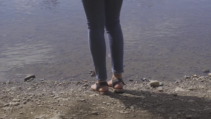 A woman stands at the edge of the beach